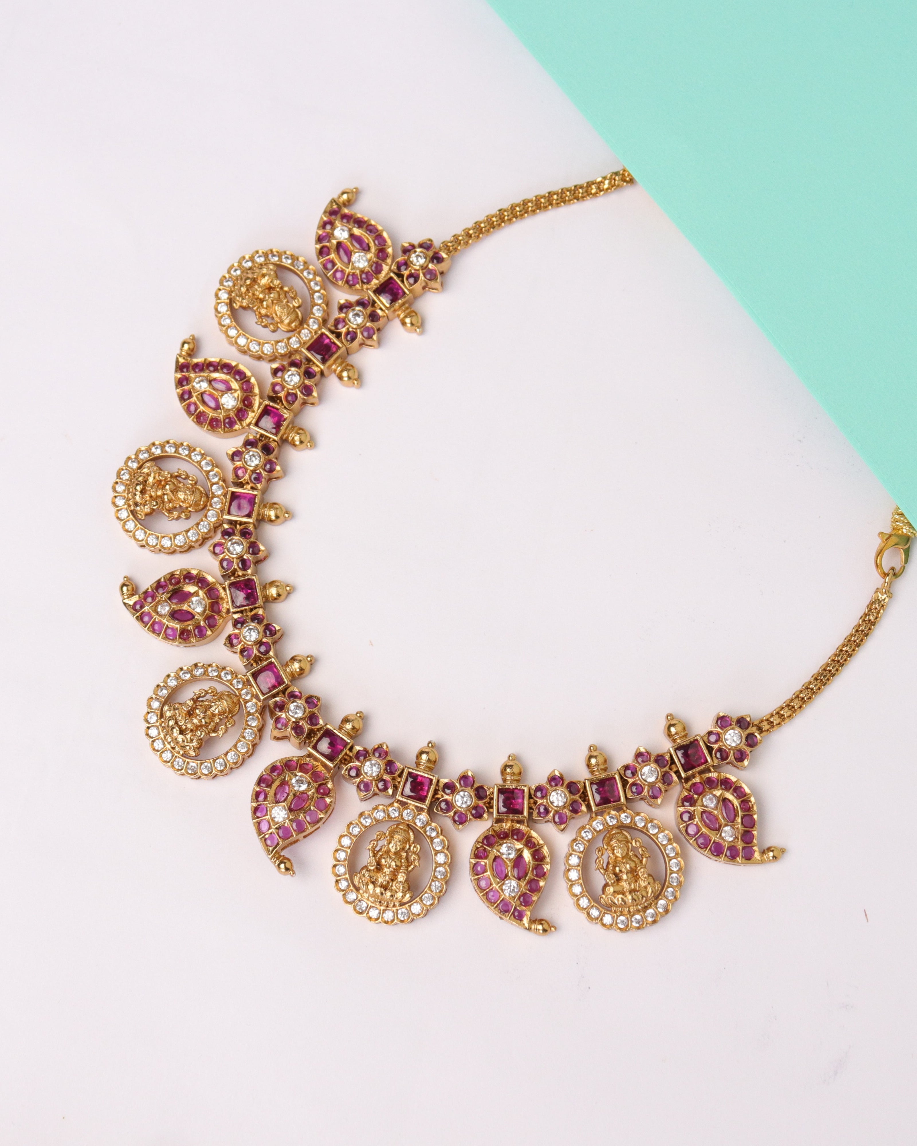 Decorative gold bracelet with charms on a white and teal background