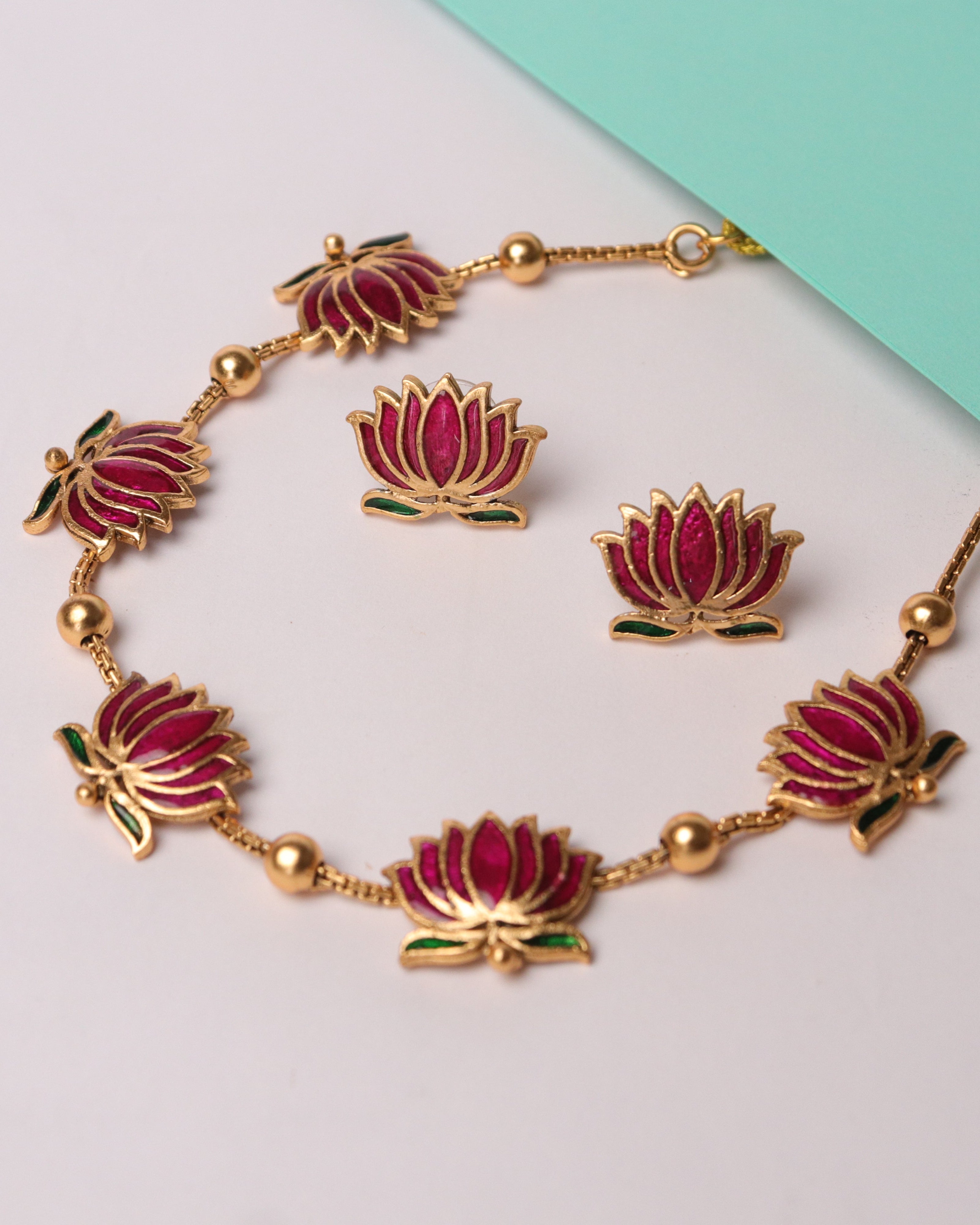 Jewelry set with bracelet and earrings featuring pink floral designs on a light gray background.