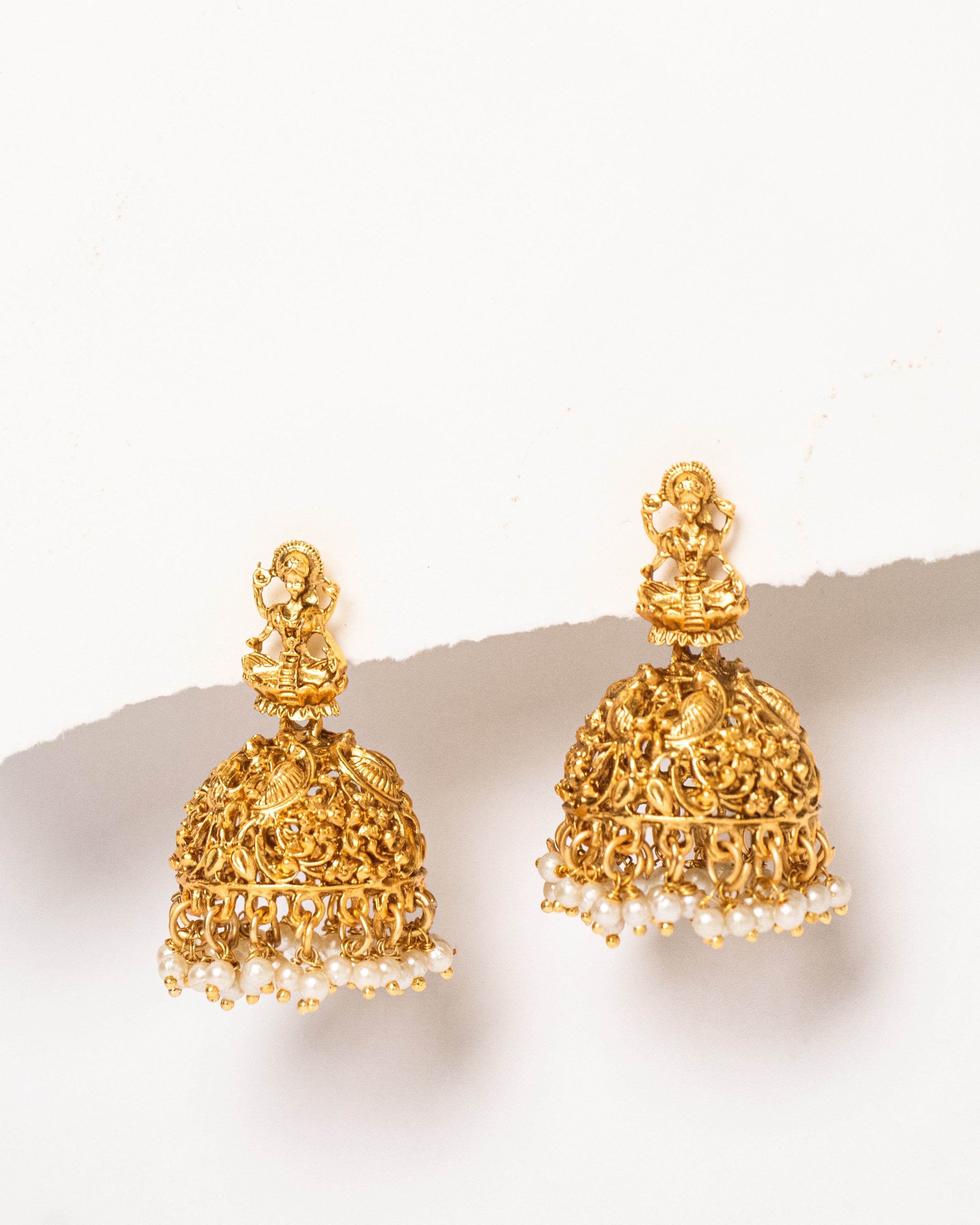 Gold earrings with intricate designs on a white background