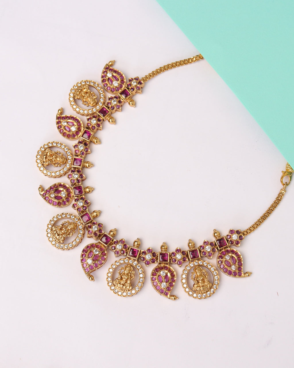 Decorative gold bracelet with charms on a white and teal background