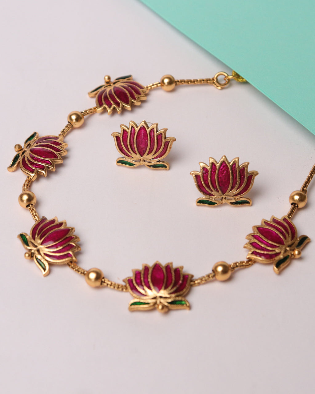 Jewelry set with bracelet and earrings featuring pink floral designs on a light gray background.